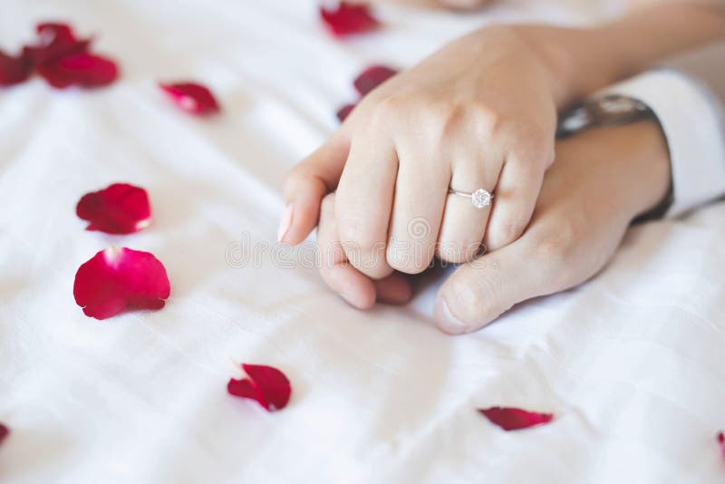El cierre encima de amantes de los pares del novio de la mano muestra para llevar el anillo de bodas en la novia que lleva a cabo imagen de archivo El cierre encima de amantes de los pares del novio de la mano muestra para llevar el anillo de bodas en la novia que lleva a cabo imagen de archivo