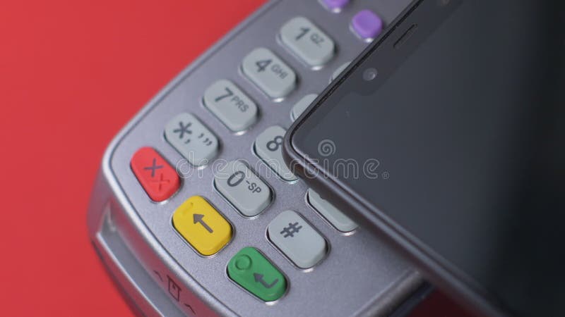 El cliente paga con un teléfono negro a través de un terminal gris que se coloca metrajes