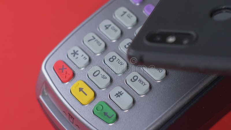 El cliente paga con un teléfono negro a través de un terminal gris que se coloca metrajes