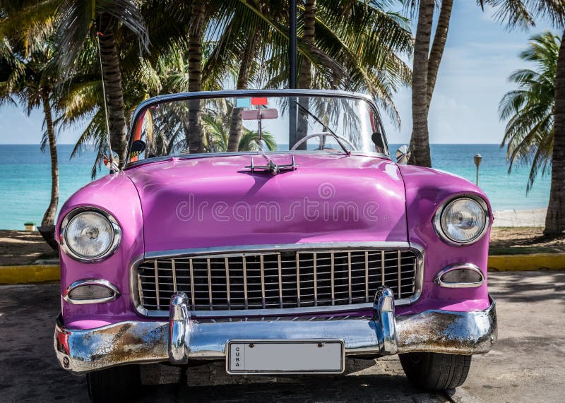 El coche clásico americano rosado de HDR Cuba parqueó debajo de las palmas cerca de la playa en Varadero foto de archivo libre de regalías El coche clásico americano rosado de HDR Cuba parqueó debajo de las palmas cerca de la playa en Varadero foto de archivo libre de regalías
