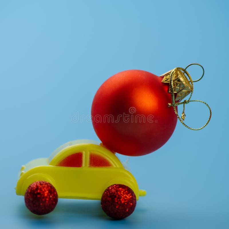 El coche del juguete lleva una bola roja del árbol de navidad imagen de archivo libre de regalías El coche del juguete lleva una bola roja del árbol de navidad imagen de archivo libre de regalías