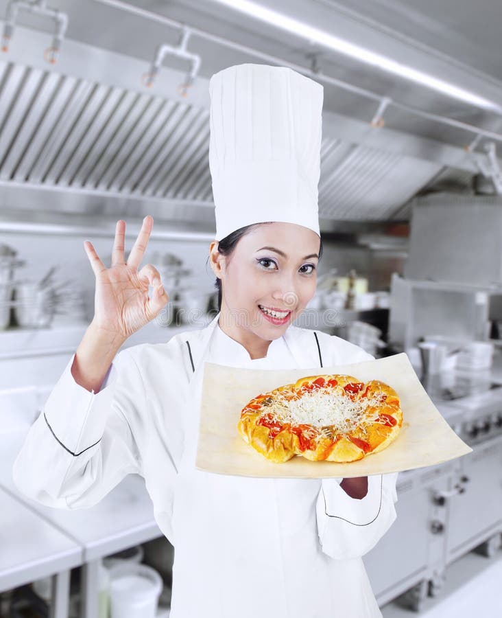 Cocinero hermoso y pizza deliciosa imagen de archivo libre de regalías Cocinero hermoso y pizza deliciosa imagen de archivo libre de regalías