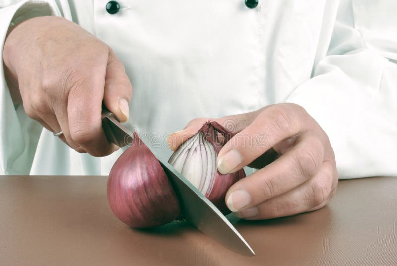 El cocinero de sexo femenino corta una cebolla de la lila foto de archivo El cocinero de sexo femenino corta una cebolla de la lila foto de archivo