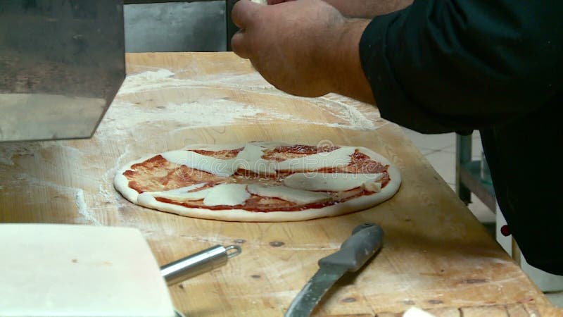 El cocinero prepara la pizza con queso y la salchicha