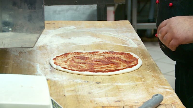 El cocinero prepara la pizza con queso y la salchicha