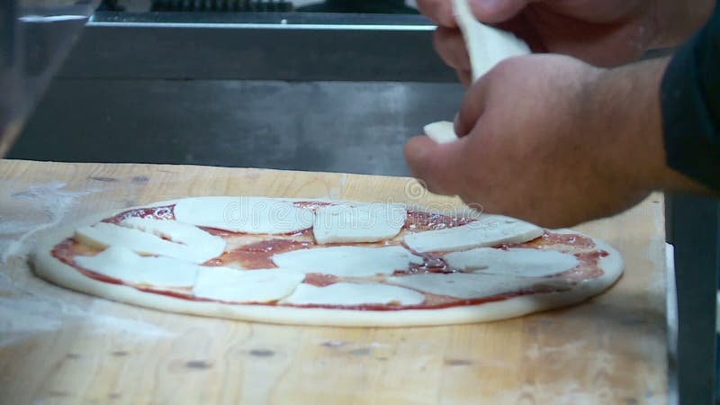 El cocinero prepara la pizza con queso y la salchicha