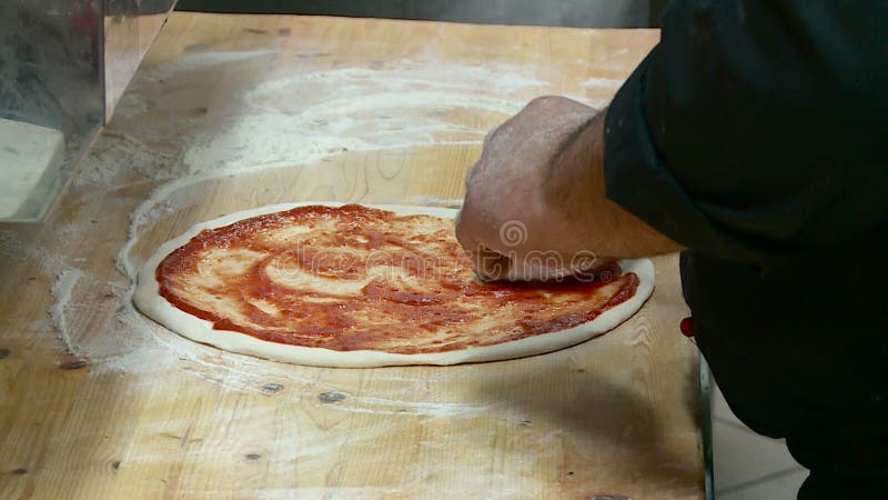 El cocinero prepara la pizza con queso y la salchicha