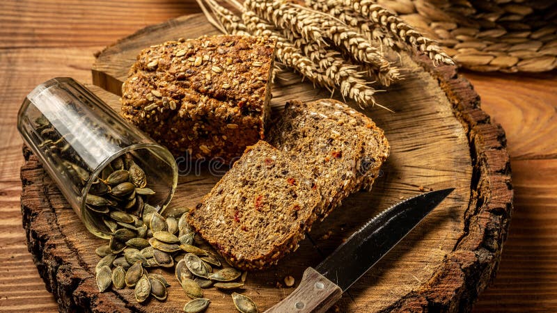El concepto de consumición sana Pan entero del grano con las semillas de la baya del goji, calabaza, en una placa en un fondo de fotografía de archivo El concepto de consumición sana Pan entero del grano con las semillas de la baya del goji, calabaza, en una placa en un fondo de fotografía de archivo