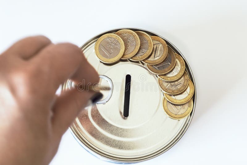 El concepto de dinero Una hucha bajo la forma de cuentas de una lata y, al lado de la hucha, de dinero y monedas se presenta fotografía de archivo libre de regalías El concepto de dinero Una hucha bajo la forma de cuentas de una lata y, al lado de la hucha, de dinero y monedas se presenta fotografía de archivo libre de regalías