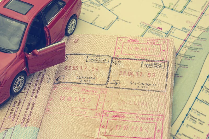 El concepto de viaje en coche: el pasaporte con los sellos de la frontera Correspondencia de la ciudad Modelo rojo del coche Proc foto de archivo libre de regalías El concepto de viaje en coche: el pasaporte con los sellos de la frontera Correspondencia de la ciudad Modelo rojo del coche Proc foto de archivo libre de regalías