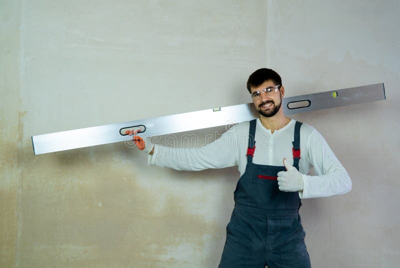 El constructor sonriente con demostraciones de la regla de la construcción manosea con los dedos para arriba en espacio libre int imágenes de archivo libres de regalías El constructor sonriente con demostraciones de la regla de la construcción manosea con los dedos para arriba en espacio libre int imágenes de archivo libres de regalías