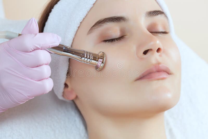 El cosmetologist hace el procedimiento Microdermabrasion de la piel facial de una mujer hermosa, joven en un salón de belleza fotos de archivo libres de regalías El cosmetologist hace el procedimiento Microdermabrasion de la piel facial de una mujer hermosa, joven en un salón de belleza fotos de archivo libres de regalías