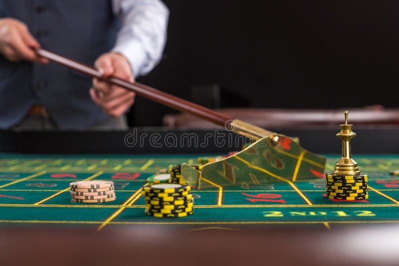 El crupié recoge microprocesadores usando el palillo en casino foto de archivo El crupié recoge microprocesadores usando el palillo en casino foto de archivo