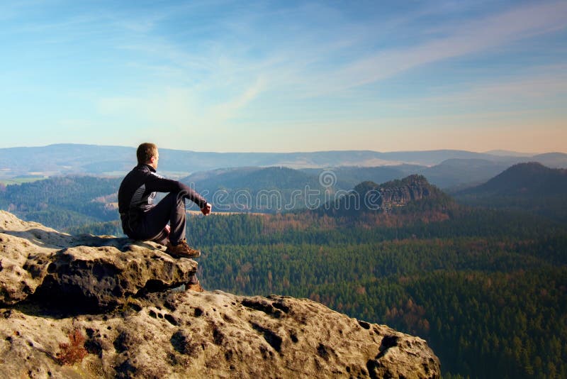El deportista en negro se sienta en el pico de la roca de la piedra arenisca en imperios de la roca parquea y vigilando el valle foto de archivo libre de regalías El deportista en negro se sienta en el pico de la roca de la piedra arenisca en imperios de la roca parquea y vigilando el valle foto de archivo libre de regalías