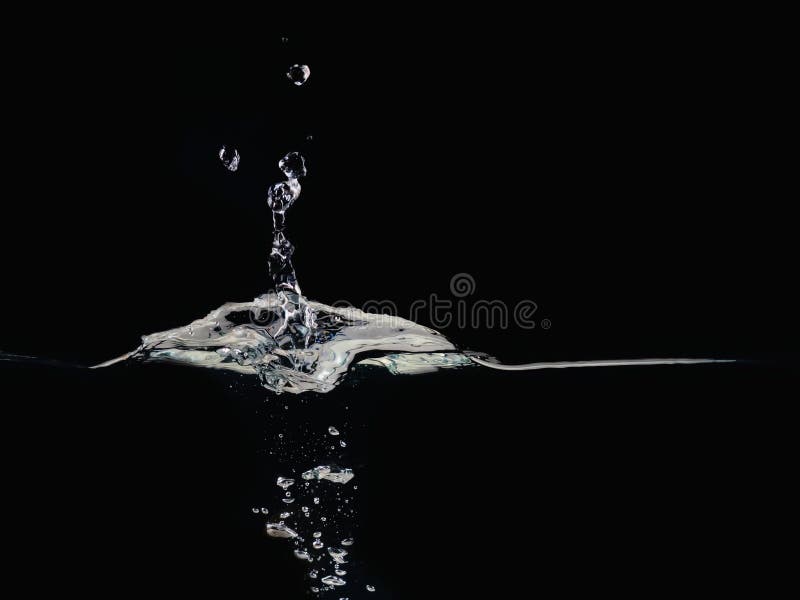 El descenso del agua salpica en la superficie que hace burbujas y ondulando, aislado en fondo negro, ciérrese encima de la visión fotos de archivo libres de regalías El descenso del agua salpica en la superficie que hace burbujas y ondulando, aislado en fondo negro, ciérrese encima de la visión fotos de archivo libres de regalías
