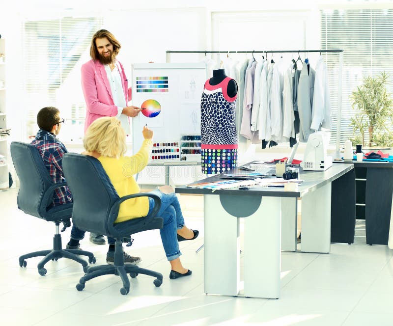 El diseñador y su equipo eligen la tela para la ropa imagen de archivo El diseñador y su equipo eligen la tela para la ropa imagen de archivo