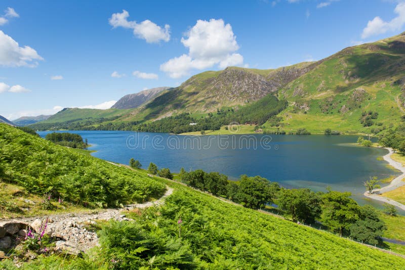 El distrito BRITÁNICO Buttermere Cumbria Inglaterra Reino Unido del lago en un día de verano soleado hermoso rodeada cerca derrib imagen de archivo libre de regalías El distrito BRITÁNICO Buttermere Cumbria Inglaterra Reino Unido del lago en un día de verano soleado hermoso rodeada cerca derrib imagen de archivo libre de regalías
