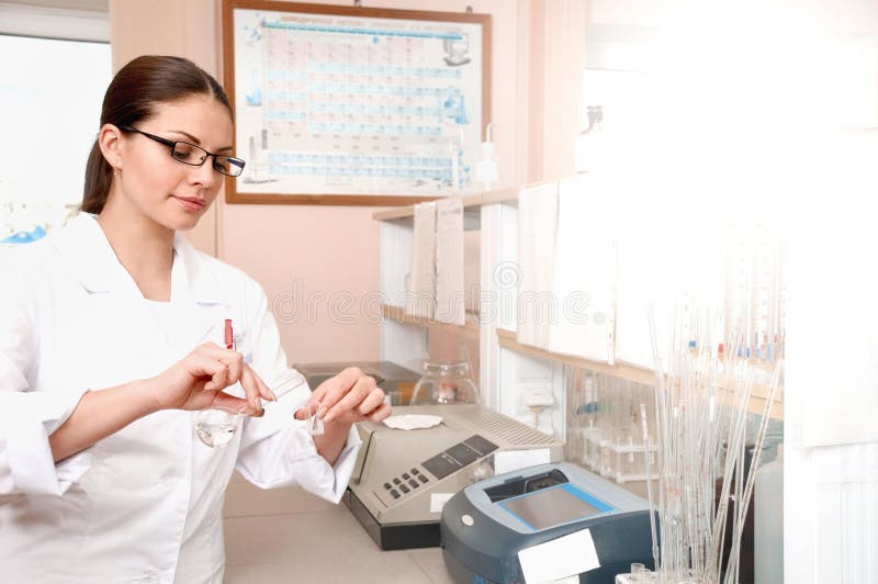 El doctor de sexo femenino en uniforme del blanco está sosteniendo los frascos mientras que trabaja en el laboratorio fotografía de archivo El doctor de sexo femenino en uniforme del blanco está sosteniendo los frascos mientras que trabaja en el laboratorio fotografía de archivo