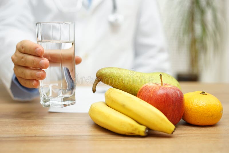 El doctor está ofreciendo el agua y la fruta después de que lea diagnostique Healt