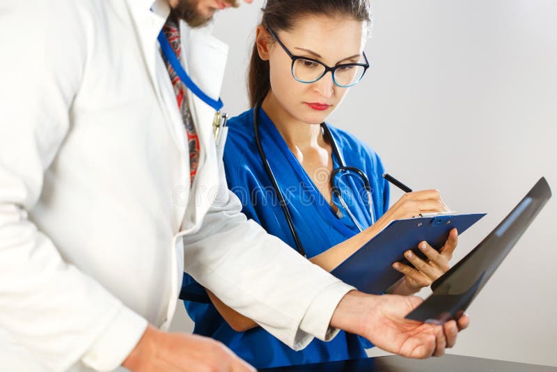 El doctor mira la radiografía y dice a enfermera qué tratamiento a prescribir fotos de archivo libres de regalías El doctor mira la radiografía y dice a enfermera qué tratamiento a prescribir fotos de archivo libres de regalías