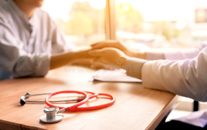 El doctor sostiene las manos y las hojas que confortan a consejeros al patie foto de archivo El doctor sostiene las manos y las hojas que confortan a consejeros al patie foto de archivo