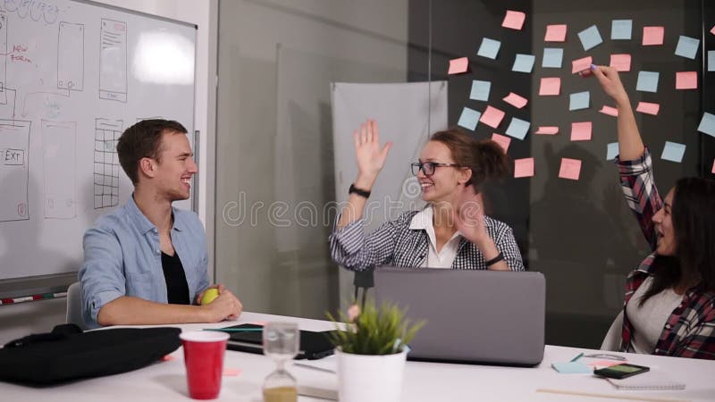 El donante acertado feliz del equipo del negocio de la gente joven los altos fives gesticula mientras que él ríe y anima su éxito