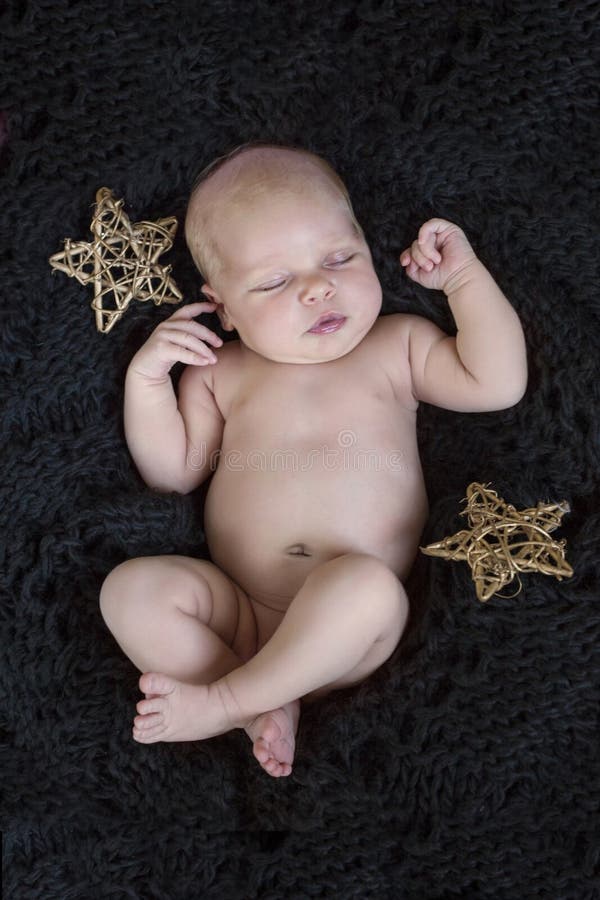 A baby girl sleeping on a black blanket with stars. A baby girl sleeping on a black blanket with stars.