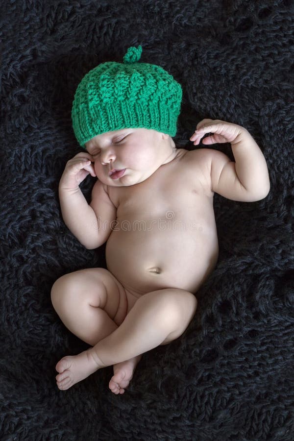A young baby girl with green cap sleeping on black wool. A young baby girl with green cap sleeping on black wool.