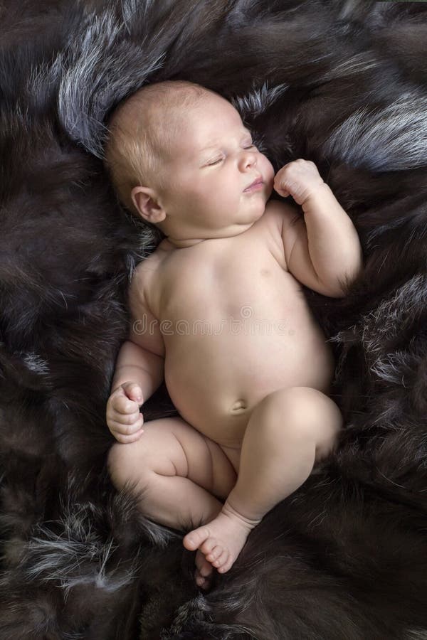 A young newborn baby girl sleeping on a fur pelt. A young newborn baby girl sleeping on a fur pelt.