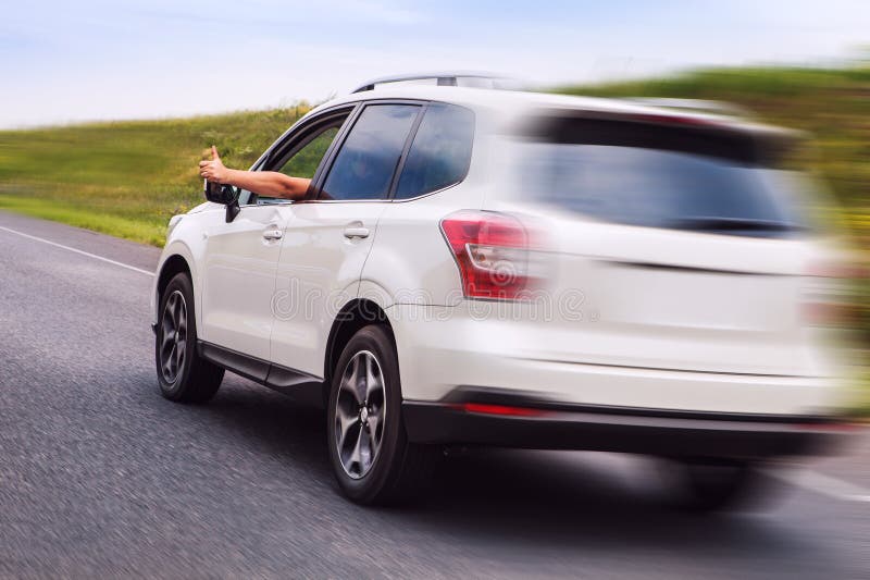 El dueño feliz del nuevo coche monta la carretera y muestra el pulgar para arriba imagen de archivo libre de regalías El dueño feliz del nuevo coche monta la carretera y muestra el pulgar para arriba imagen de archivo libre de regalías