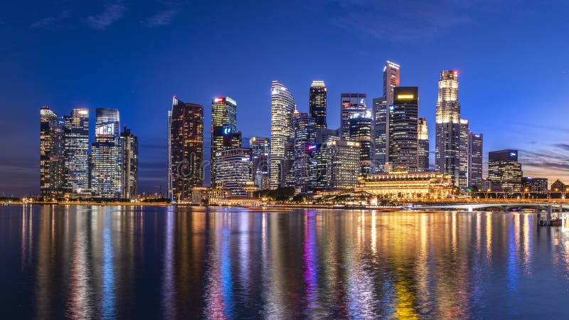 El edificio de negocios de Singapur se eleva al amanecer reflexionando sobre la bahÃa de agua en el ocaso imagen de archivo El edificio de negocios de Singapur se eleva al amanecer reflexionando sobre la bahÃa de agua en el ocaso imagen de archivo