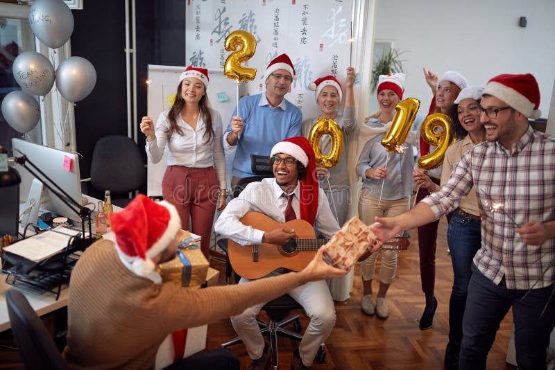 El equipo feliz del negocio tiene la diversión y baile en el sombrero de Papá Noel en los regalos del partido y del intercambio d fotos de archivo El equipo feliz del negocio tiene la diversión y baile en el sombrero de Papá Noel en los regalos del partido y del intercambio d fotos de archivo
