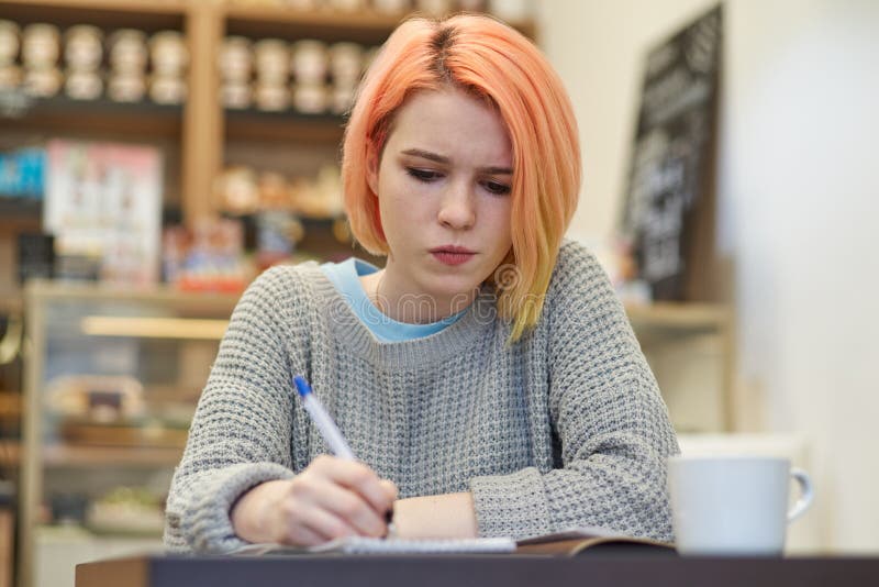 El escritor joven de la colegiala de la muchacha del estudiante hace notas en su cuaderno fotografía de archivo El escritor joven de la colegiala de la muchacha del estudiante hace notas en su cuaderno fotografía de archivo