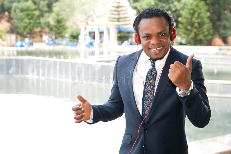 El escuchar al aire libre del hombre de negocios la música con los auriculares imagen de archivo libre de regalías El escuchar al aire libre del hombre de negocios la música con los auriculares imagen de archivo libre de regalías