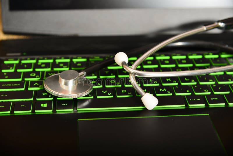 El estetoscopio está mintiendo en un teclado verde en un ordenador portátil, concepto de la reparación del mobiliario de oficinas imagen de archivo libre de regalías El estetoscopio está mintiendo en un teclado verde en un ordenador portátil, concepto de la reparación del mobiliario de oficinas imagen de archivo libre de regalías