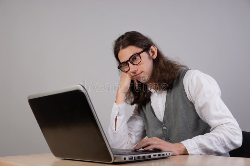 El estudiante aburrido está sentado en un ordenador portátil. El tipo es un geek que el jugador utiliza un ordenador portátil. Cur. Aburrimiento y falta de decisión sin interés del curso.
