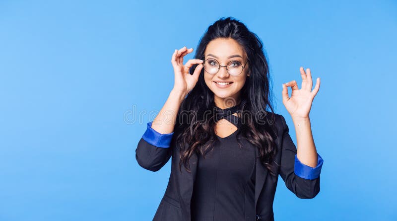 El estudiante feliz con los vidrios y una chaqueta negra que muestra los pulgares suben MUY BIEN imagen de archivo El estudiante feliz con los vidrios y una chaqueta negra que muestra los pulgares suben MUY BIEN imagen de archivo