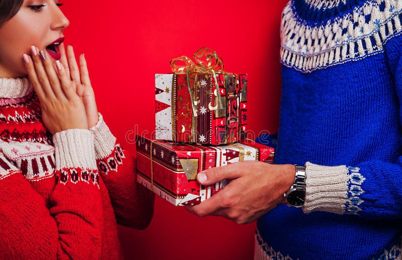 El estudio tiró de un par en suéteres islandeses Hombre que da a su novia las cajas de regalo Concepto de la Navidad o de la cele fotos de archivo El estudio tiró de un par en suéteres islandeses Hombre que da a su novia las cajas de regalo Concepto de la Navidad o de la cele fotos de archivo