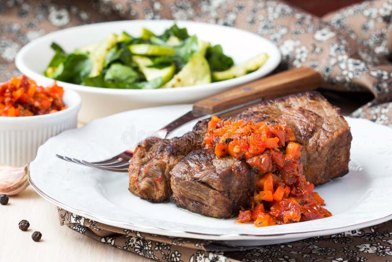 El filete de carne de vaca asado a la parrilla con la salsa de la salsa secó los tomates, pimientas rojas fotografía de archivo libre de regalías El filete de carne de vaca asado a la parrilla con la salsa de la salsa secó los tomates, pimientas rojas fotografía de archivo libre de regalías