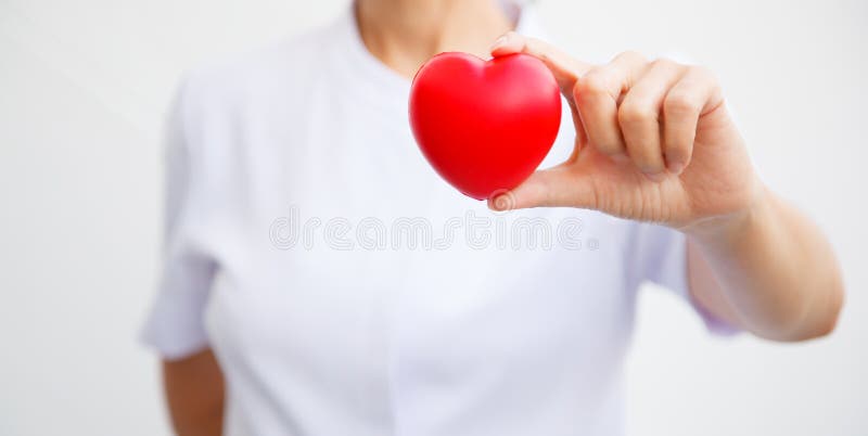 El foco selectivo del corazón rojo se sostuvo por la mano femenina del ` s de la enfermera, representando dando todo el esfuerzo