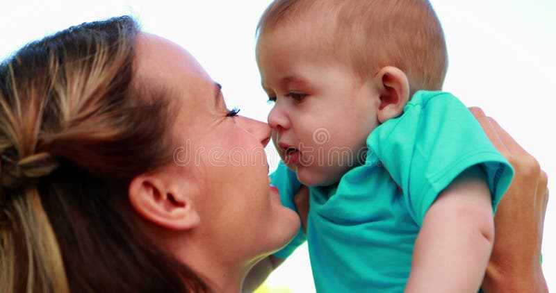 El frotamiento feliz de la madre sospecha con el hijo lindo del bebé en el parque