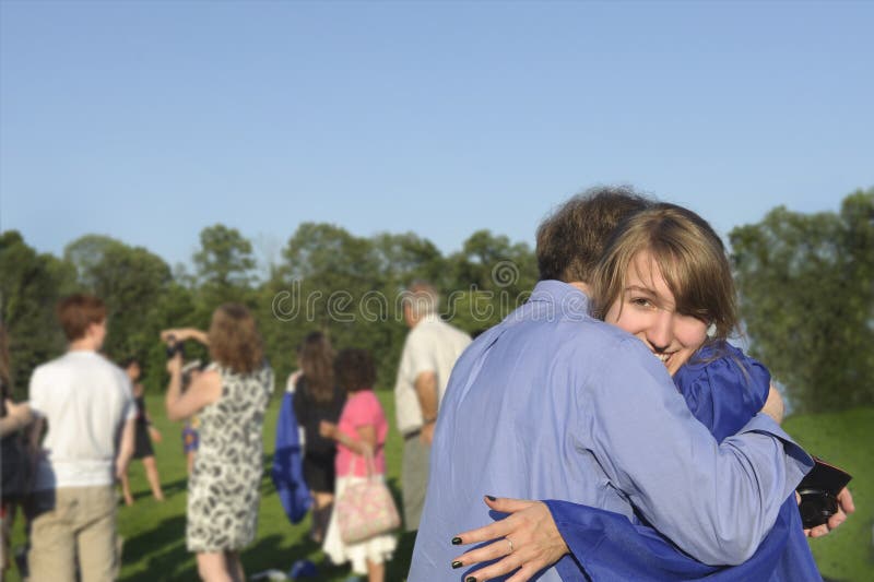 Pretty female graduate hugs her dad after commencement exercises. Although graduation marks the end of school (here high school) it is called commencement recognizing that it is a new beginning for the students as they head out into the world to explore the next phase of their lives. Altered to blur background faces. Model Releases for two in focus main subjects. Pretty female graduate hugs her dad after commencement exercises. Although graduation marks the end of school (here high school) it is called commencement recognizing that it is a new beginning for the students as they head out into the world to explore the next phase of their lives. Altered to blur background faces. Model Releases for two in focus main subjects.