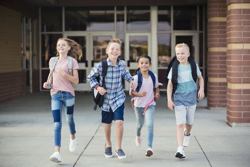 Group of school kids running as they leave elementary school at the end of day. Going home from school happy and excited. Back to school photo. Group of school kids running as they leave elementary school at the end of day. Going home from school happy and excited. Back to school photo