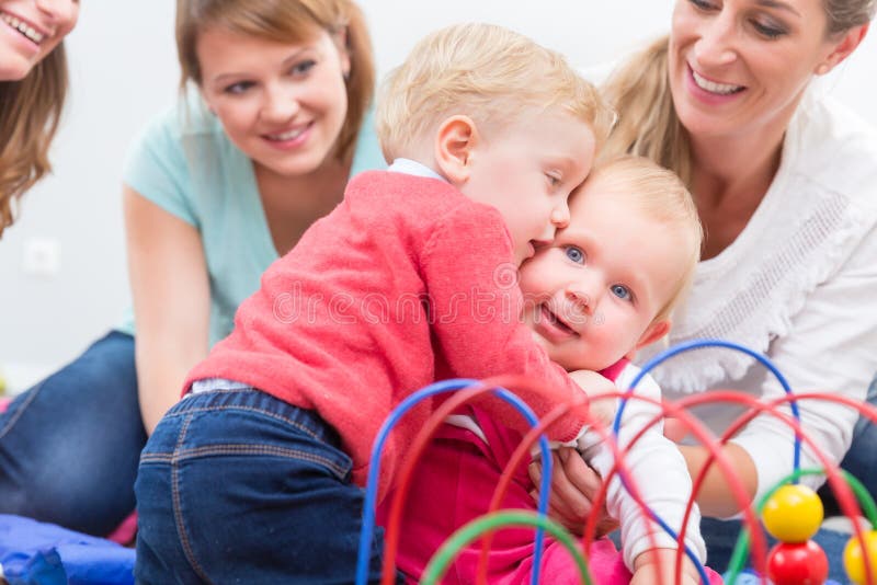 El grupo de madres jovenes felices que miran a sus bebés lindos y sanos juega fotografía de archivo libre de regalías El grupo de madres jovenes felices que miran a sus bebés lindos y sanos juega fotografía de archivo libre de regalías