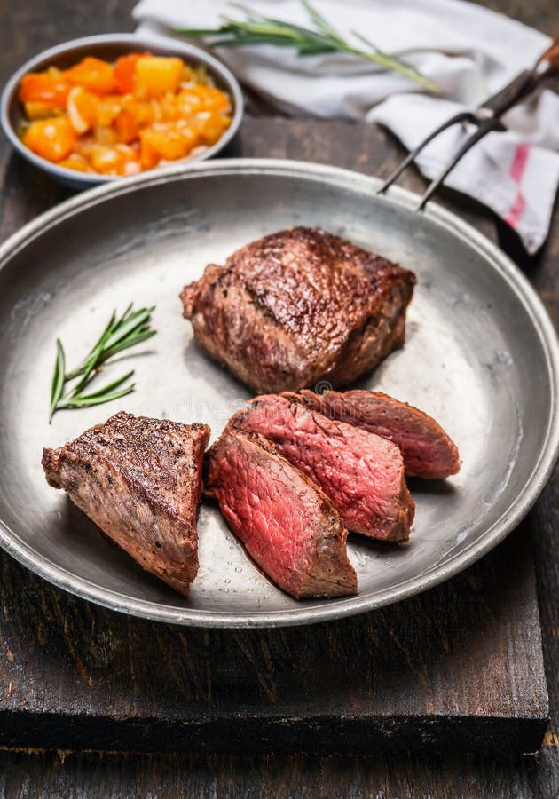 El hecho cortado asó el filete de carne de vaca, mignon de prendedero, en placa rústica del metal con la bifurcación de la carne foto de archivo El hecho cortado asó el filete de carne de vaca, mignon de prendedero, en placa rústica del metal con la bifurcación de la carne foto de archivo