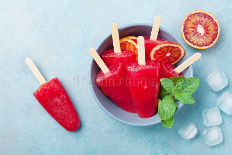 El helado o los polos adornó las hojas de menta y las rebanadas anaranjadas en la opinión de sobremesa azul Zumo de fruta congela fotos de archivo El helado o los polos adornó las hojas de menta y las rebanadas anaranjadas en la opinión de sobremesa azul Zumo de fruta congela fotos de archivo