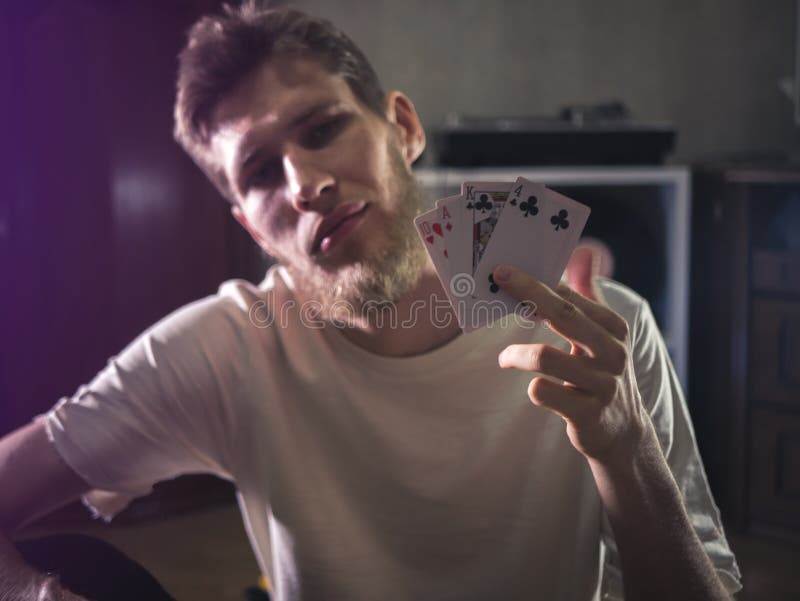 El hombre barbudo joven en tarjetas casuales del playng que se sostienen muestra el retrato de algunos trucos en casa fotos de archivo El hombre barbudo joven en tarjetas casuales del playng que se sostienen muestra el retrato de algunos trucos en casa fotos de archivo