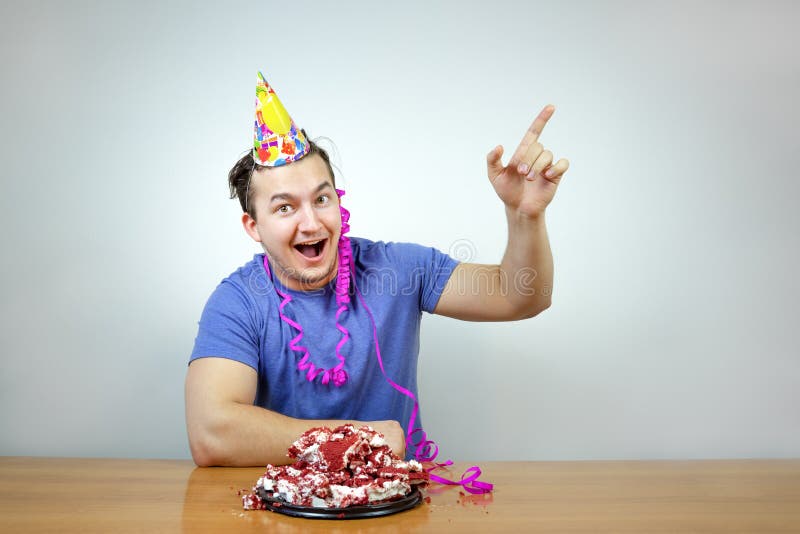El hombre caucásico hermoso emocional con el sombrero del cono de la fiesta de cumpleaños en la cabeza y arruga la torta aumenta foto de archivo El hombre caucásico hermoso emocional con el sombrero del cono de la fiesta de cumpleaños en la cabeza y arruga la torta aumenta foto de archivo