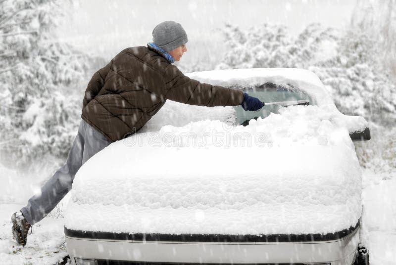 El hombre cepilla nieve de su coche imagen de archivo El hombre cepilla nieve de su coche imagen de archivo