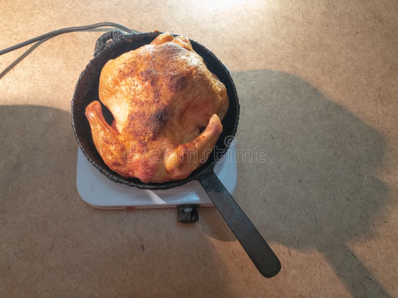 El hombre da vuelta a un pollo frito en una cacerola en un hotplate Cocinar el pollo frito fotos de archivo El hombre da vuelta a un pollo frito en una cacerola en un hotplate Cocinar el pollo frito fotos de archivo